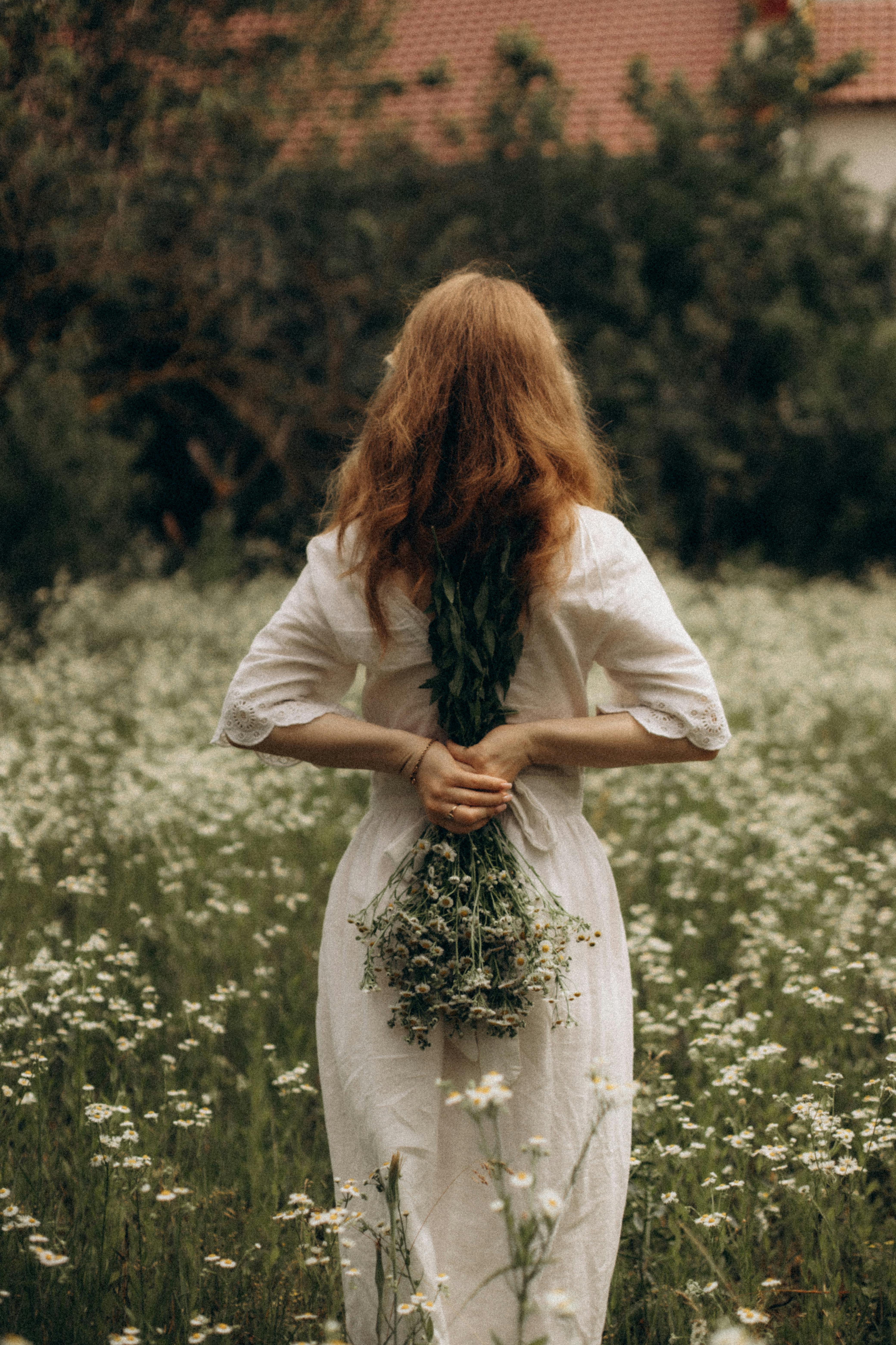 woman in white dress holding flowers in hands