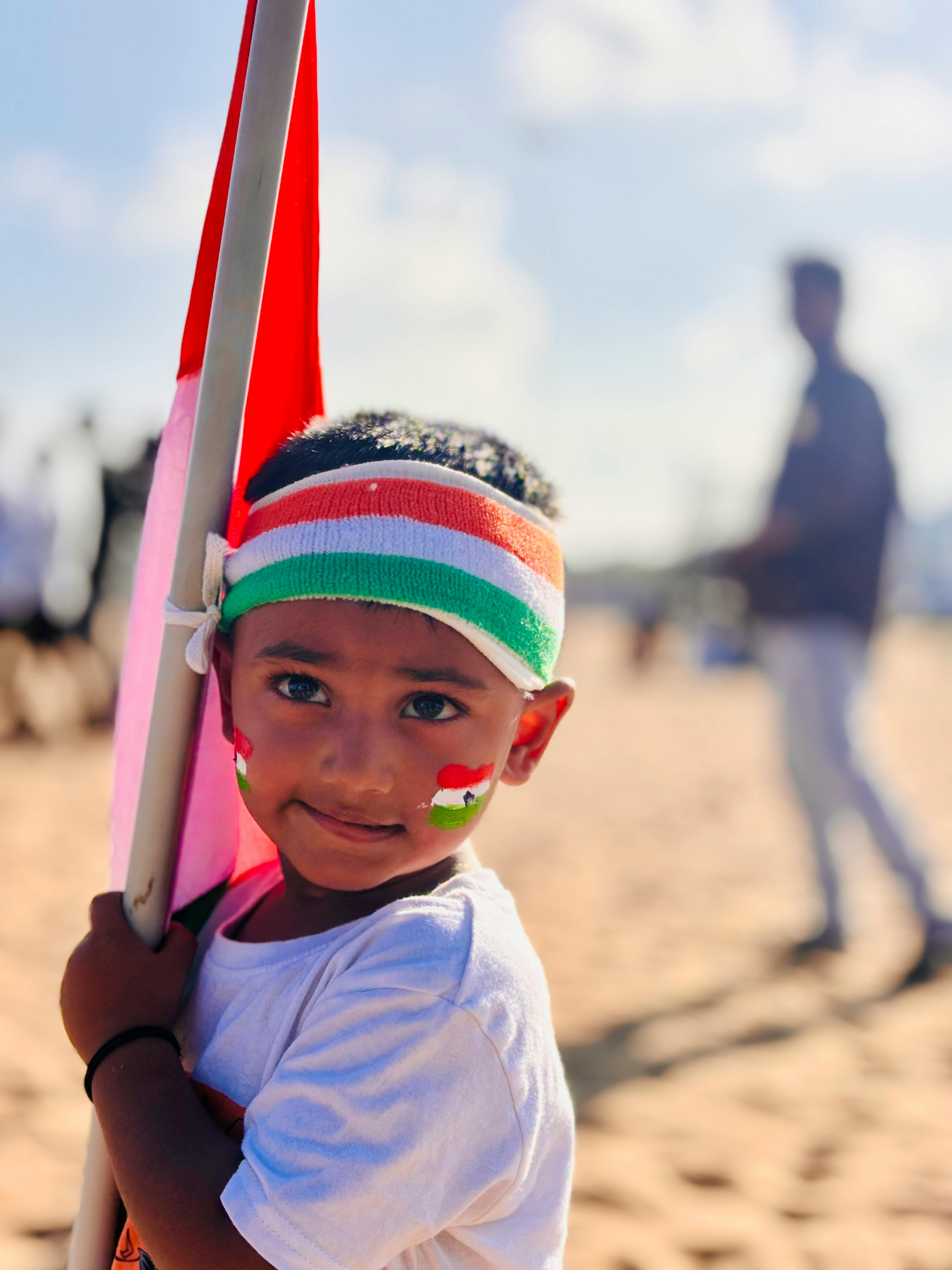 A young boy holding a flag on the beach