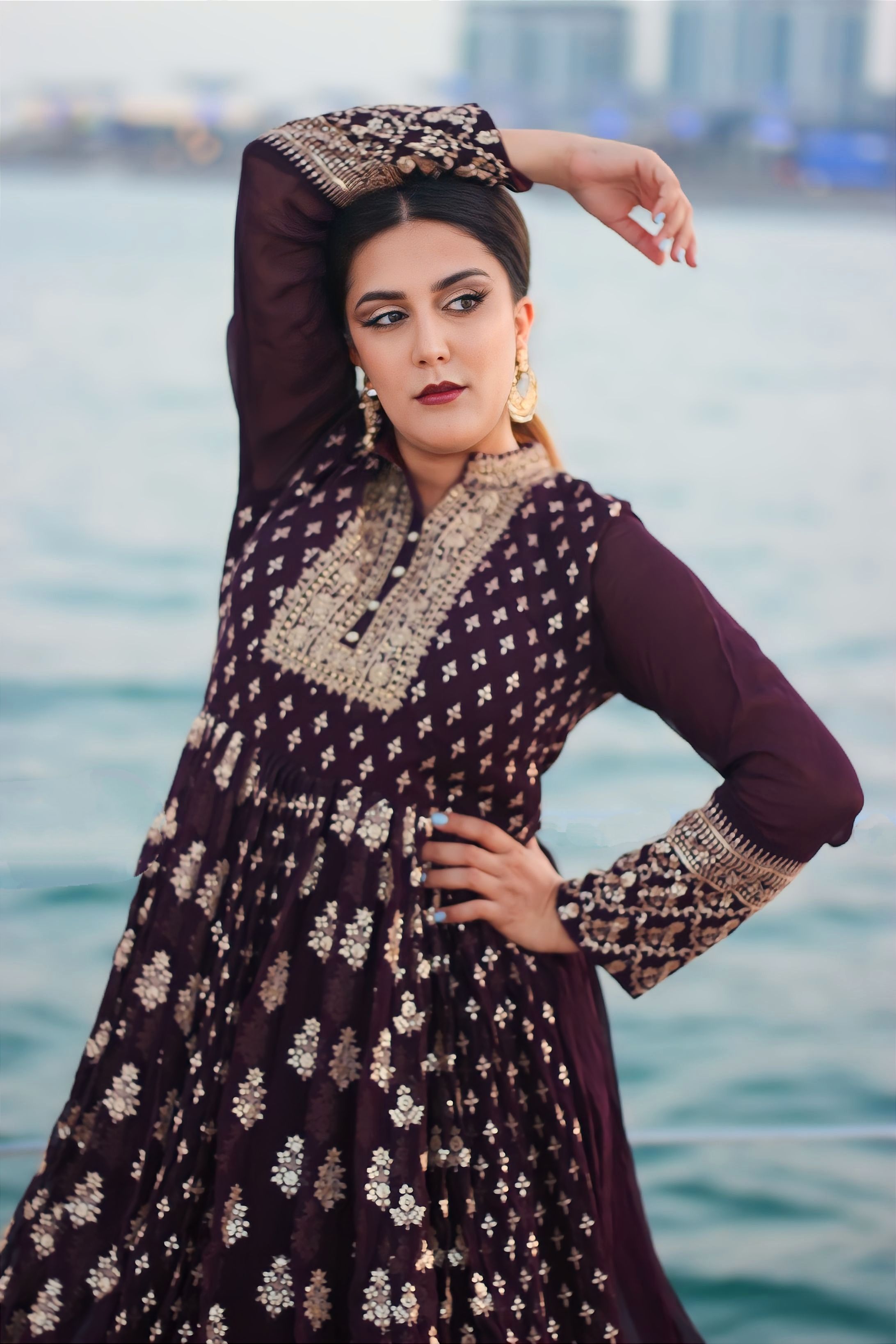 Stylish portrait of a woman in traditional attire against Dubai's waterfront.