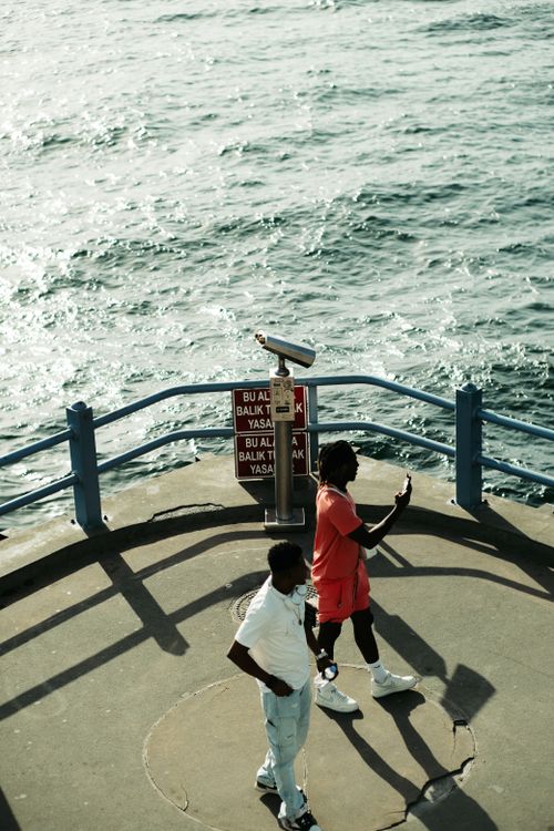 Free Two men walking on a seaside promenade in Istanbul with a tower viewer overlooking the sea. Stock Photo