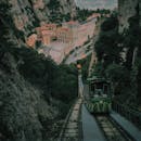 一辆历史悠久的电车行驶在绿树掩映、建筑环绕的山间小路上