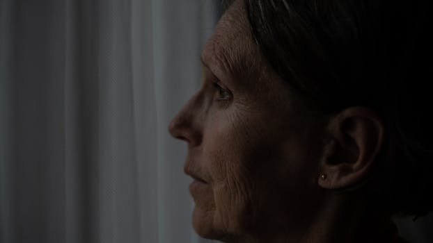 窗户旁，一位年长妇女的侧影若有所思
