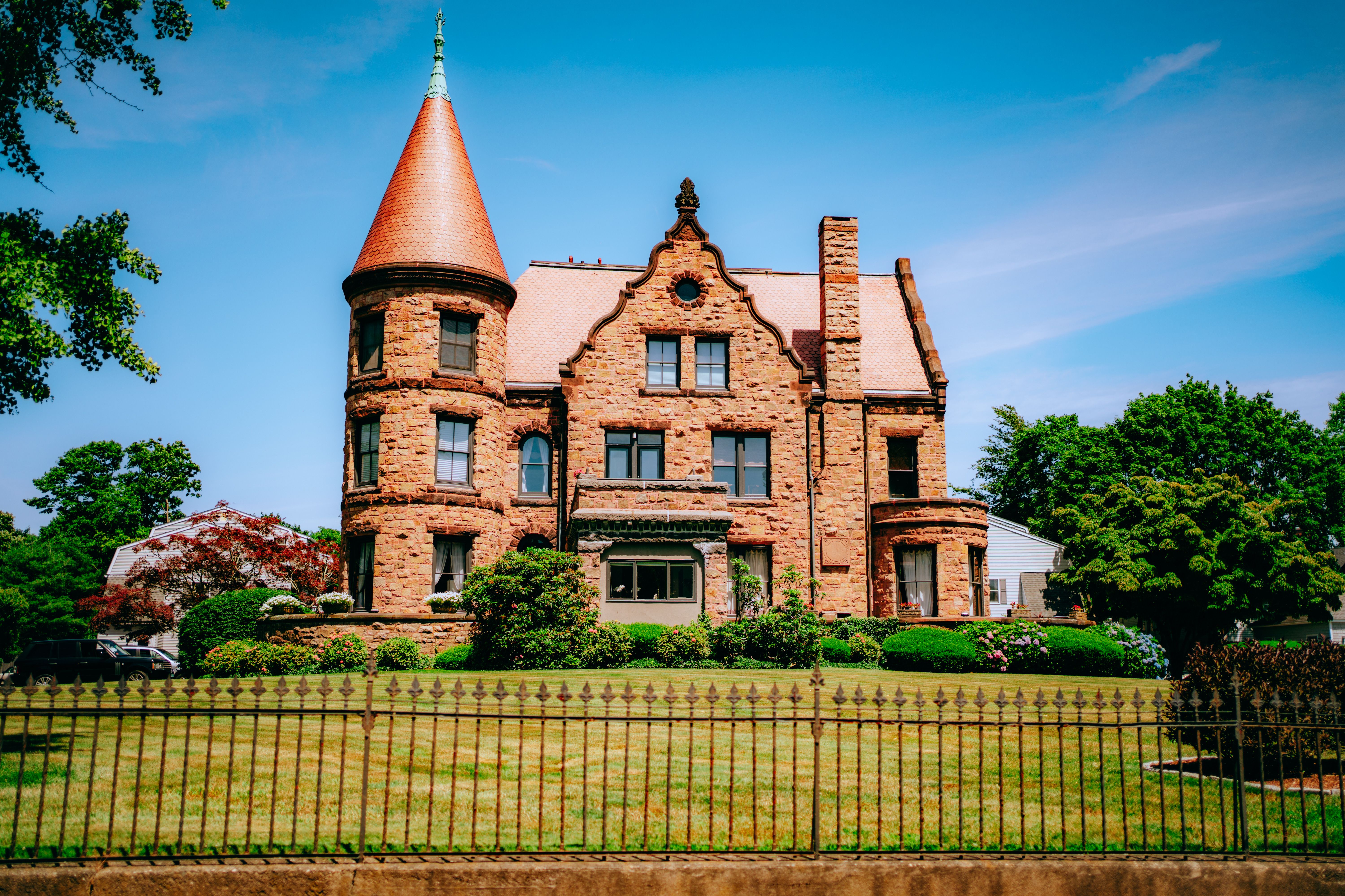 Beautiful historic brick mansion with a unique tower and lush gardens.