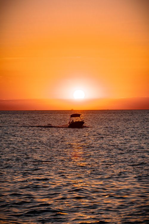 Free A serene silhouette of a boat against a vibrant sunset on the sea in Yalova, Türkiye. Stock Photo