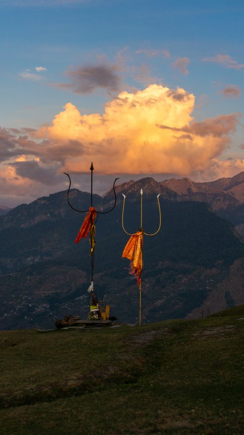 Free Tridents adorned with fabric on a hilltop in Bijli, India, under a vibrant sunset sky. Stock Photo