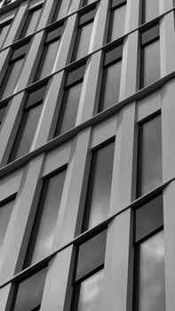 Black and white image capturing modern urban architecture with reflective glass windows and symmetrical lines.