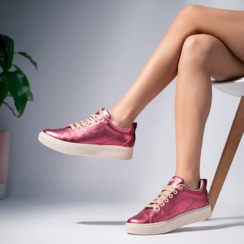 Close-up of fashionable pink sneakers worn by a woman in a studio setting.