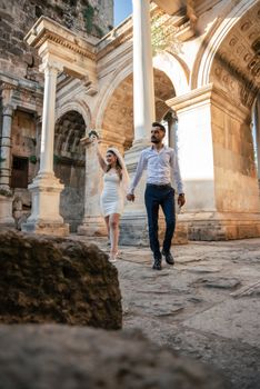 Bride and groom walking hand in hand through historic ruins, celebrating their wedding day with joy.
