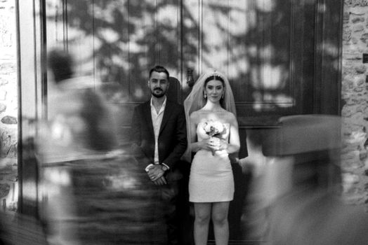 Romantic black and white photo of a wedding couple standing together outdoors with blurred motion effect.
