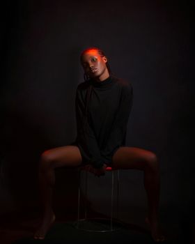 Artistic studio portrait of a young woman with dramatic red lighting and shadows.
