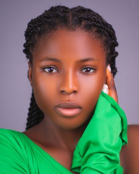 Vibrant portrait of a beautiful woman with braids and green clothing, captured in a studio.