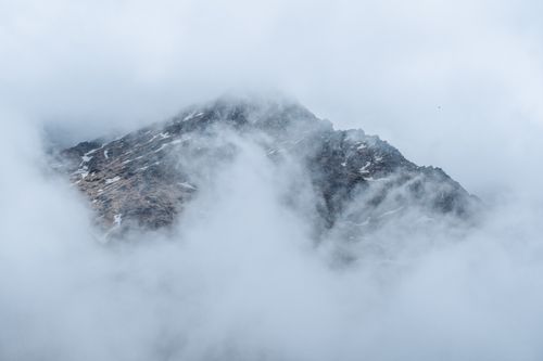 Free Dramatic view of a rocky mountain peak enveloped in soft clouds. Stock Photo
