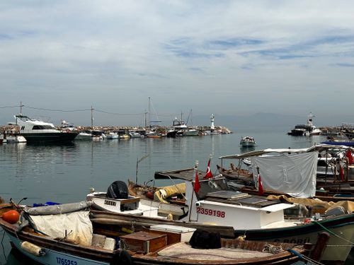 Free A picturesque harbor scene in İzmir, Türkiye, featuring boats, a lighthouse, and calm waters. Stock Photo