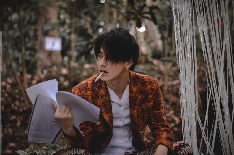 Photo Of Man Smoking While Holding Papers