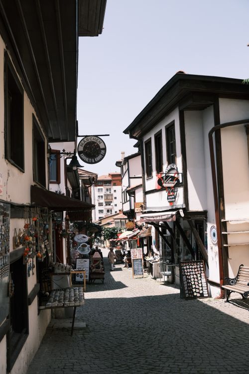 Free A picturesque narrow street in a European village with classic architecture and local shops under a clear sky. Stock Photo
