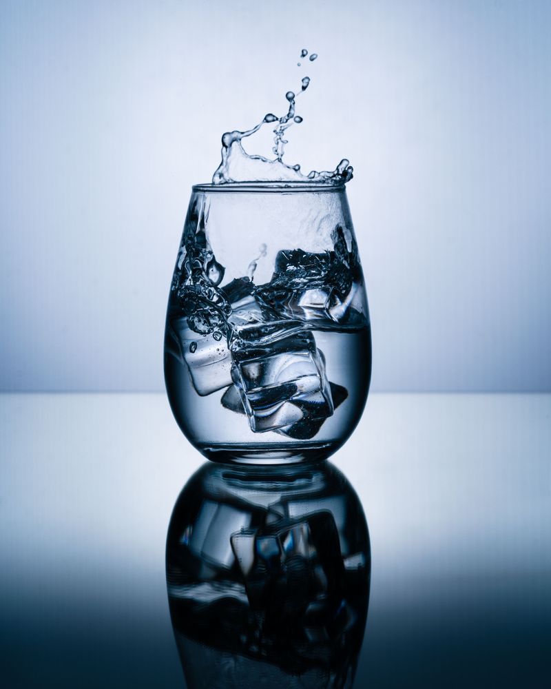 A dynamic shot of water with ice cubes splashing against a blue background