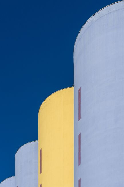 Abstract view of blue and yellow silos in Oslo against a clear blue sky, showcasing modern architecture.