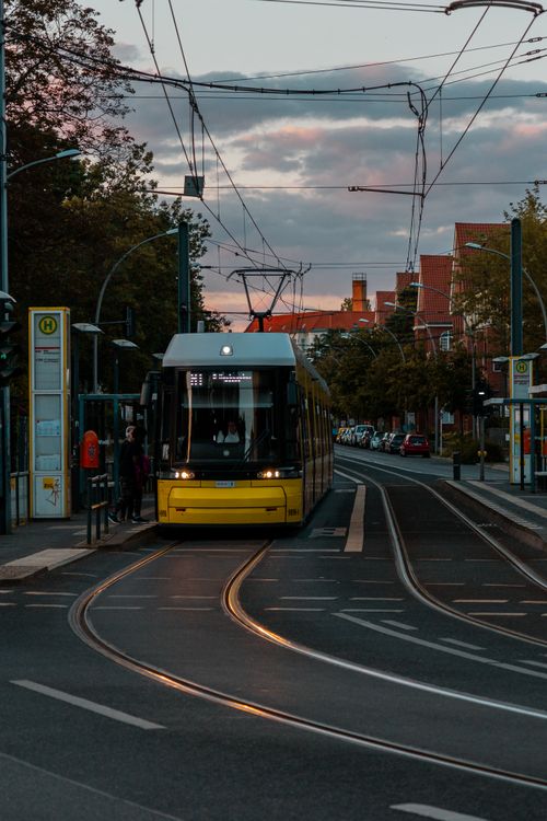 Free A tram approaches a city street stop at dusk, offering public transportation in an urban environment. Stock Photo