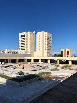 A modern urban scene showcasing tall skyscrapers and a central circular plaza.