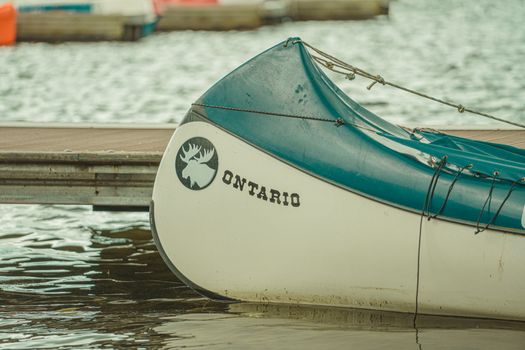 Close-up of a canoe with Ontario branding moored at a pier on a calm waterbody.