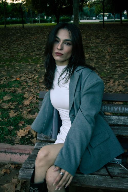 Free Woman in fashionable attire on a park bench surrounded by autumn leaves. Stock Photo