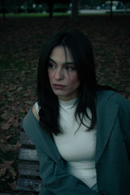 Free A woman with long black hair sitting pensively on a park bench in autumn. Stock Photo