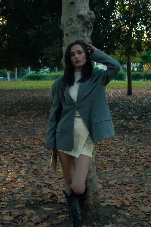 Free Elegant model poses in a fall park wearing a gray jacket and mini dress, surrounded by autumn leaves. Stock Photo