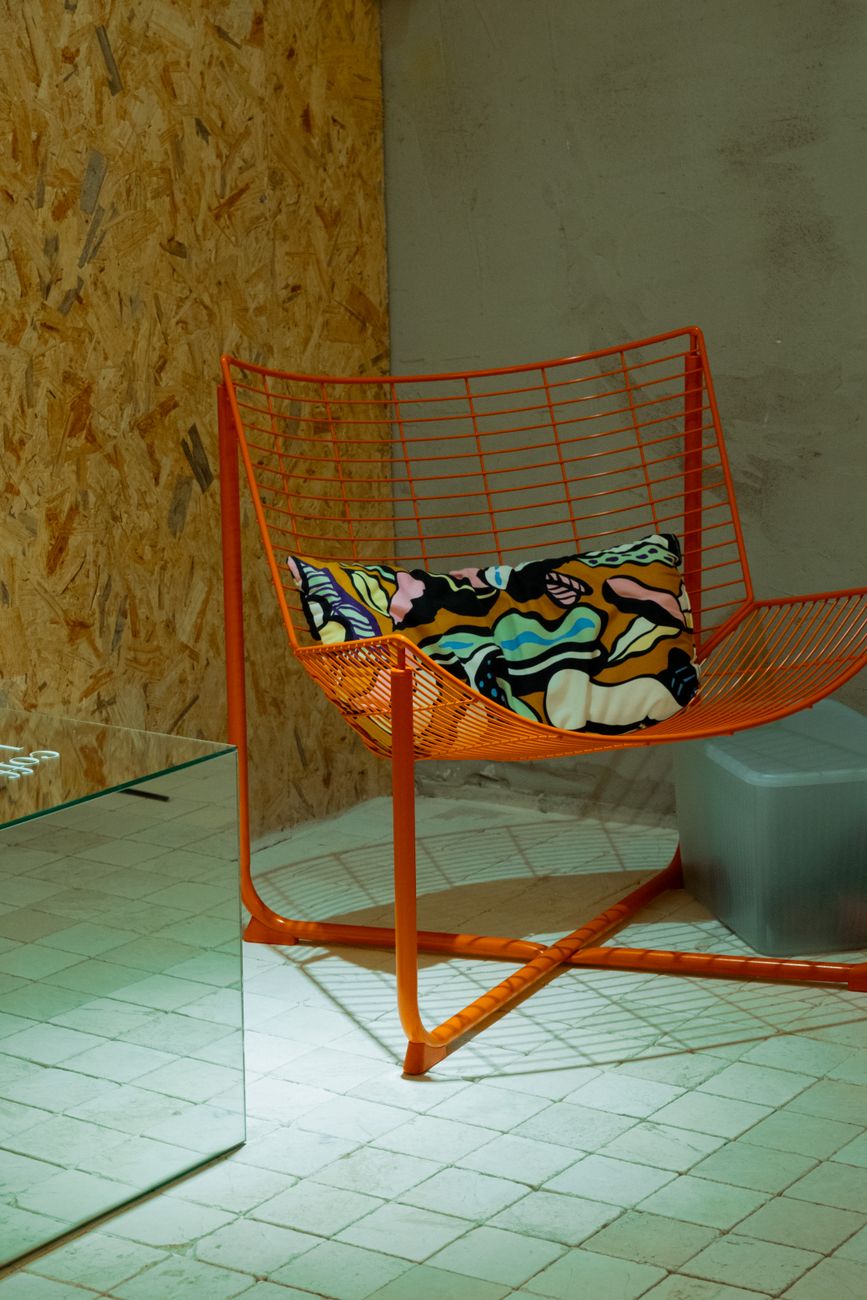 An orange wire chair with a patterned cushion, the kind of playful object that can change the mood of a room