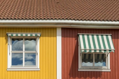 Free Captivating facade of a house in Oslo with yellow and red walls and striped awnings. Stock Photo