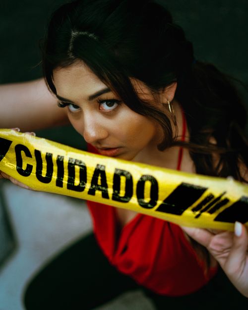 Free Young woman in red top holding caution tape, conveying intensity and alertness. Stock Photo