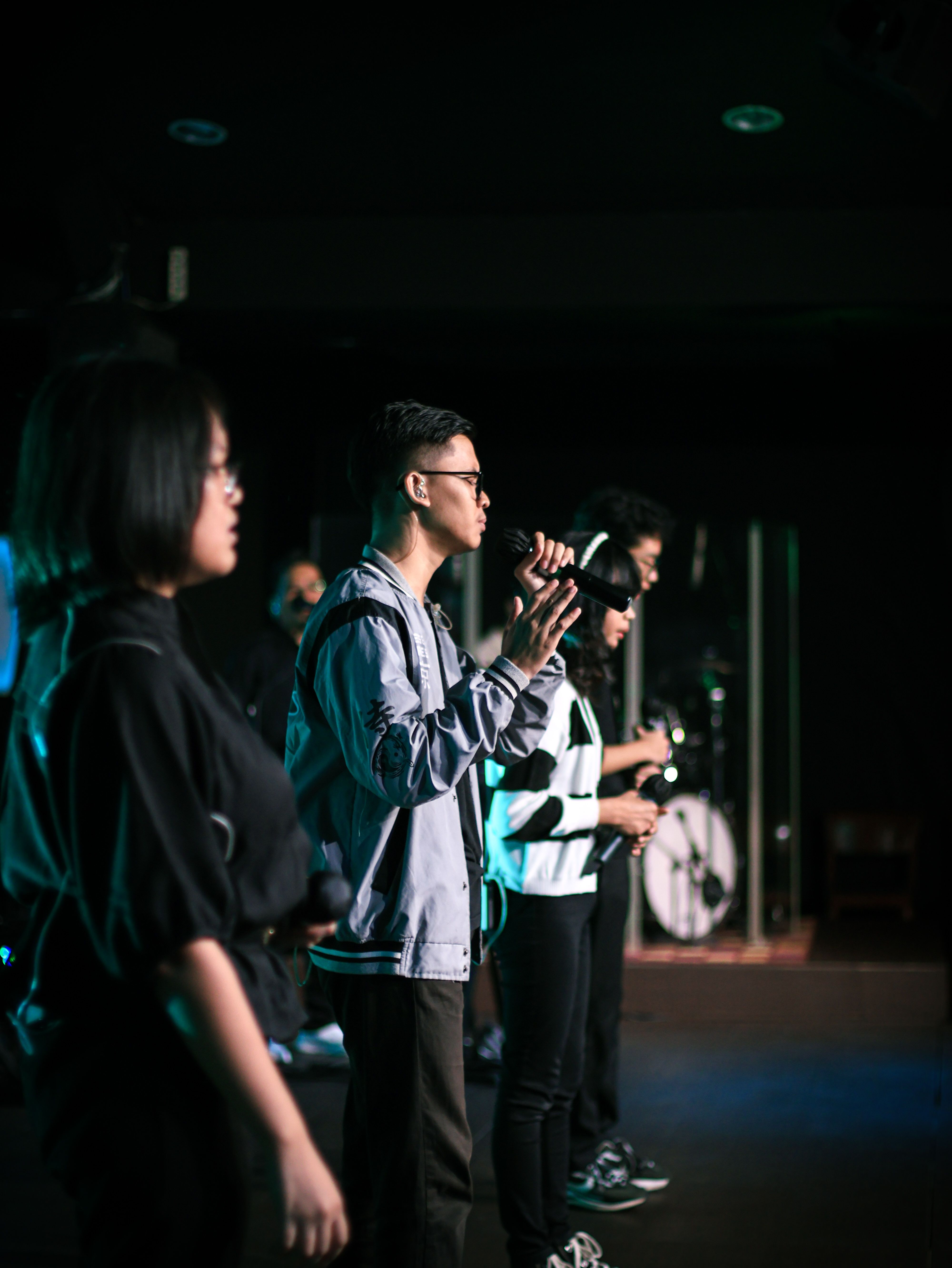 Group of singers performing on stage with microphones at night