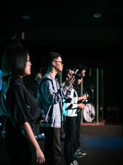 Singers lined up on a dim stage with microphones — Raymond Aquila on Pexels