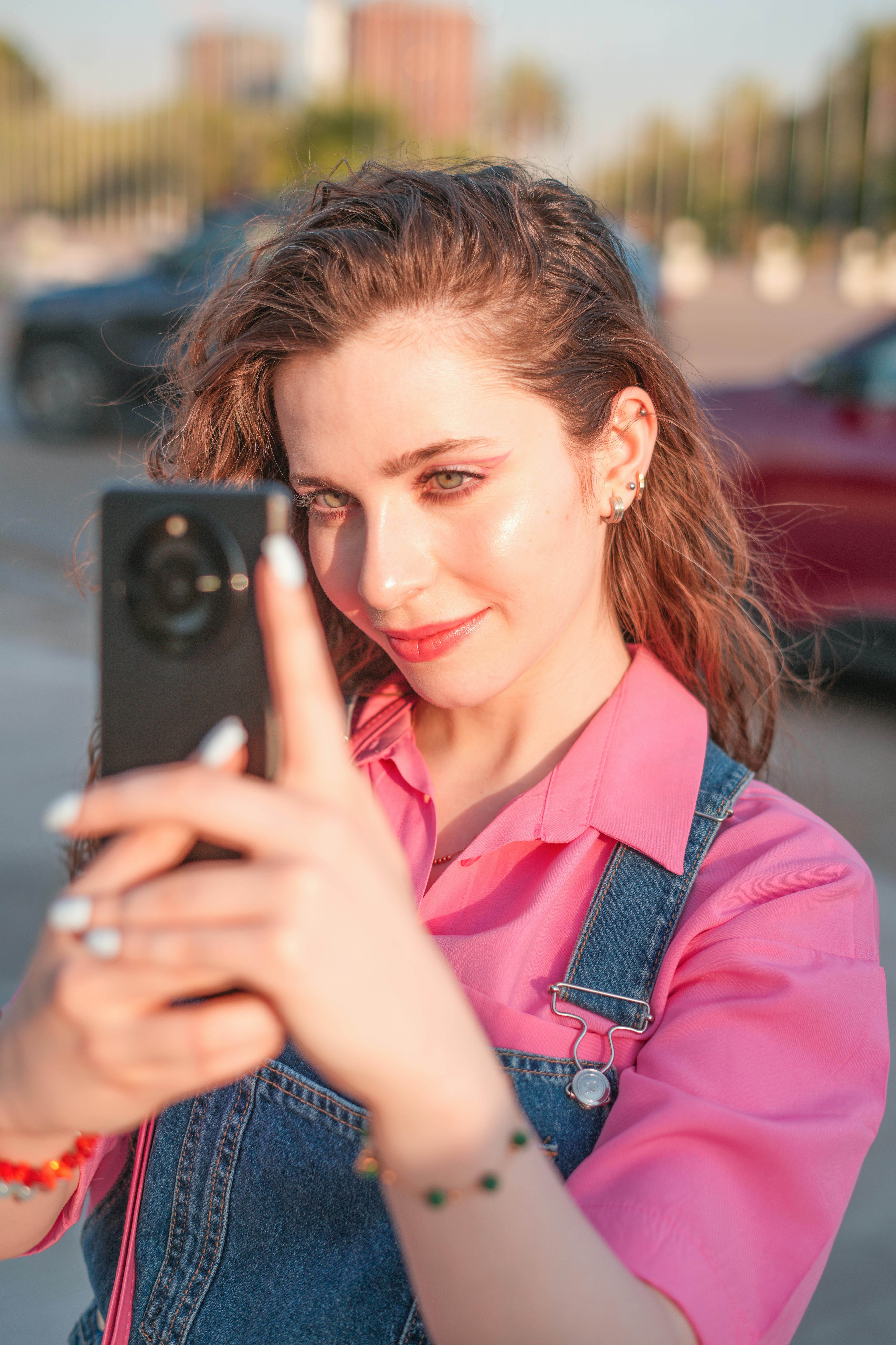 A young woman with brown hair takes a selfie on a sunny day outdoors in Baghdad, Iraq.