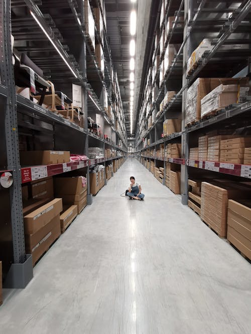 Person Sitting on Ground Between Brown Cardboard Boxes