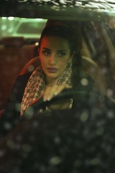 Portrait of an elegant woman driving a car in Baghdad, reflecting a moody and glamorous vibe.