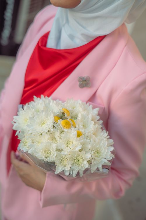Free Middle Eastern woman in hijab with a flower bouquet, wearing a pink jacket. Stock Photo
