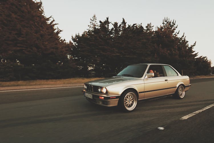 Old Car Riding On Asphalt Road