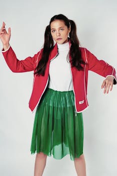 Model poses confidently in vibrant red and green outfit during studio photoshoot.