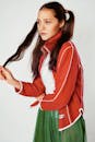 一位长发年轻女子身着红色夹克和绿色裙子，在工作室拍摄时尚肖像