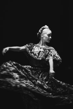 Graceful Mexican dancer swirls in traditional dress, captured in dramatic black and white.