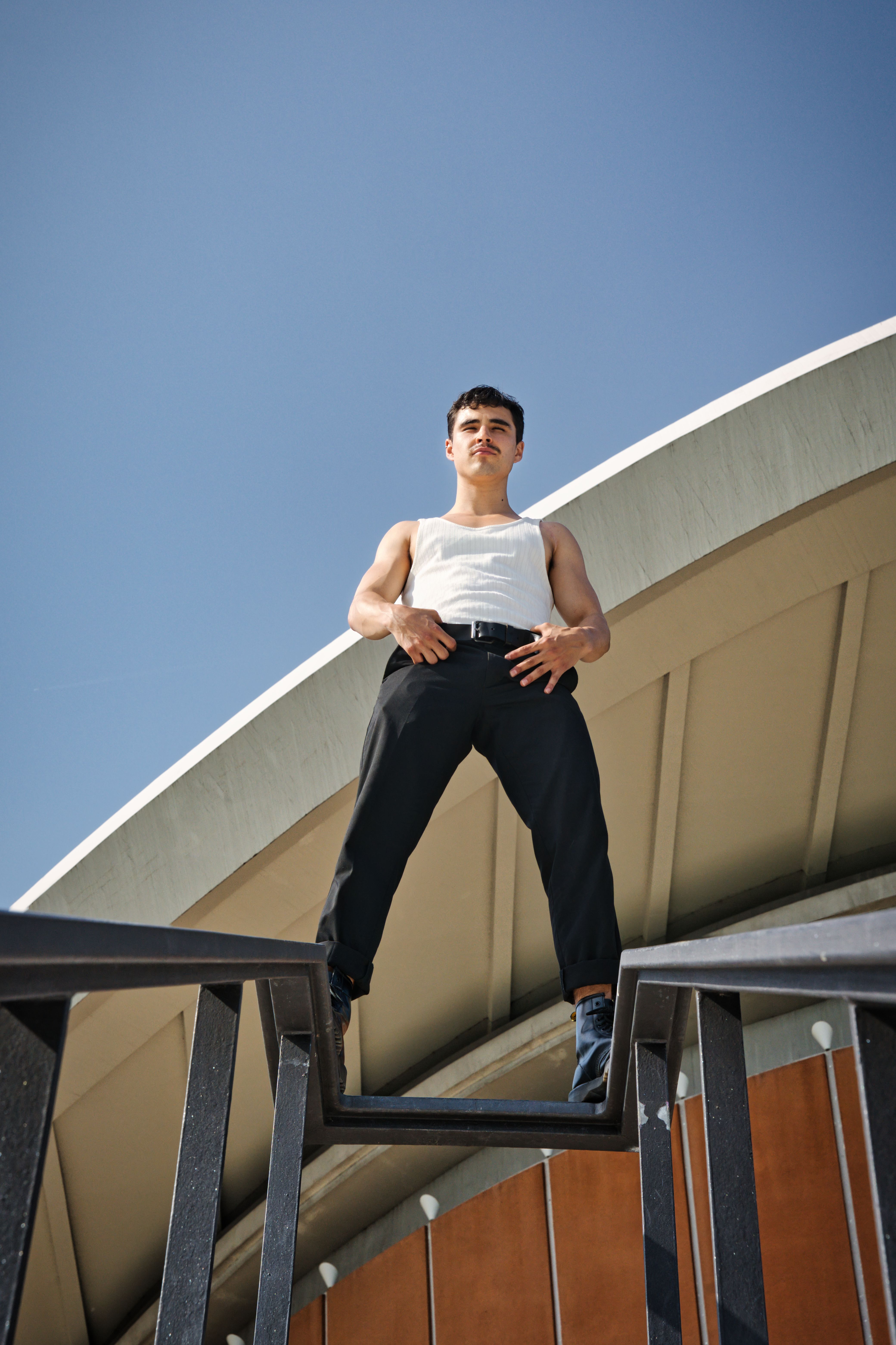 Man in White Tank Top Standing on Railing · Free Stock Photo