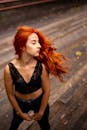 一位红发时尚女子身穿黑色蕾丝露脐上衣，在户外自信地摆着姿势
