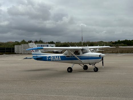 Light aircraft stationary on a runway under cloudy skies in Silveira, Portugal.