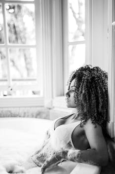 一个女人的黑白肖像在窗边的泡沫浴中显得很放松