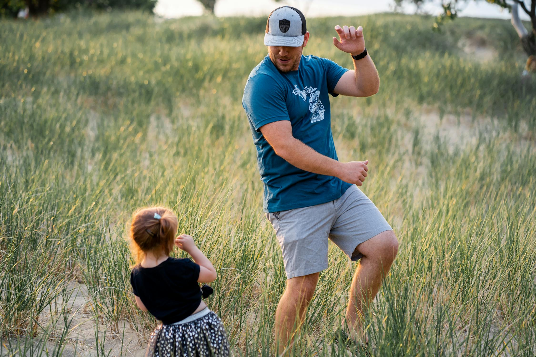 Father with his young daughter playing in a field. 
