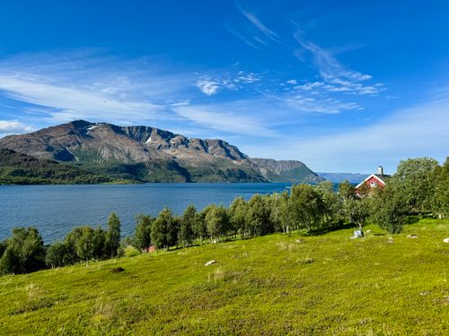 Free Beautiful landscape featuring a mountain, lake, and a quaint cottage surrounded by lush greenery. Stock Photo