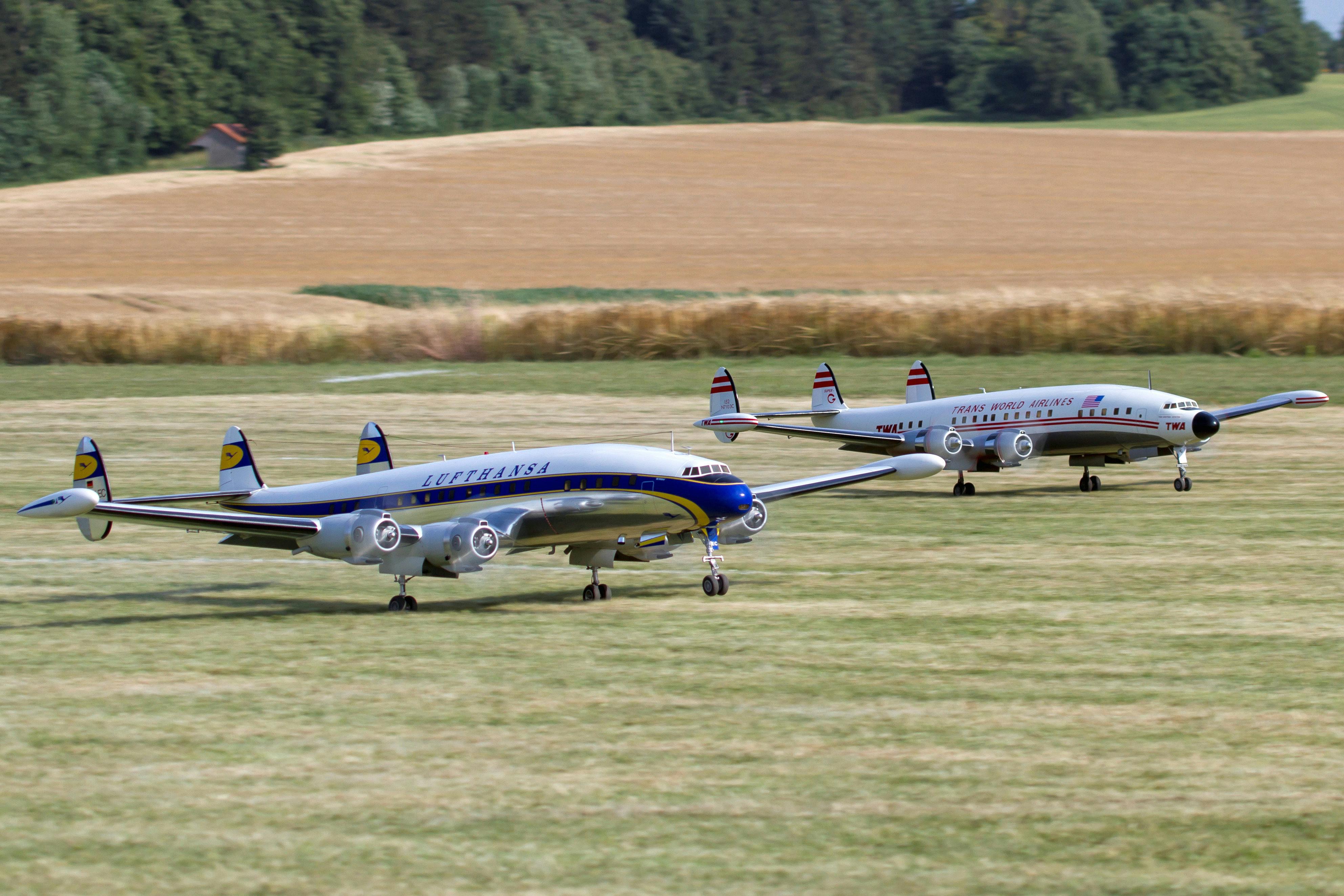 Two scale model airplanes on a rural runway, evoking classic aviation era.