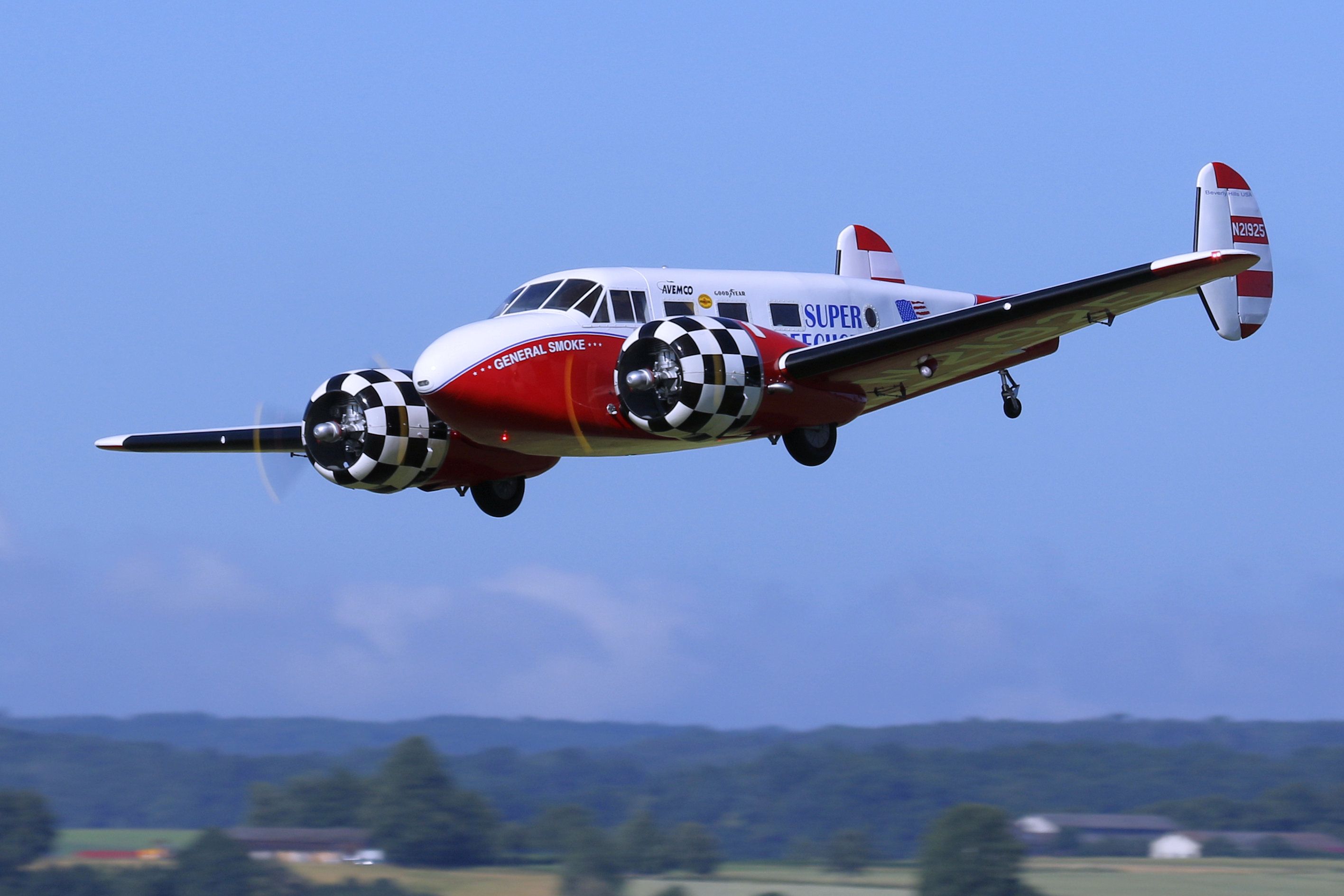 a small airplane flying in the air with a checkered flag