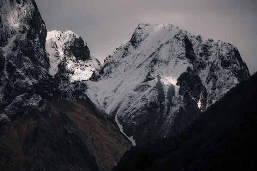 Stunning view of snowy mountain peaks under a moody dusk sky, highlighting natural beauty.