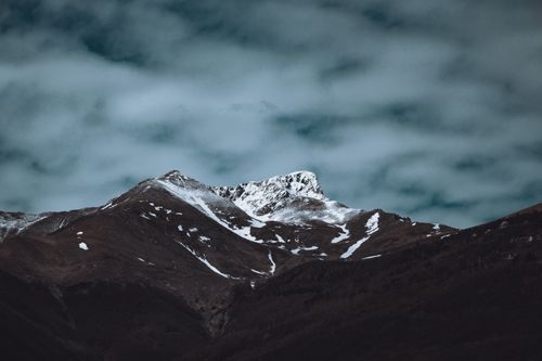 Free Dramatic view of a snow-capped mountain peak with a cloudy sky in the background. Stock Photo